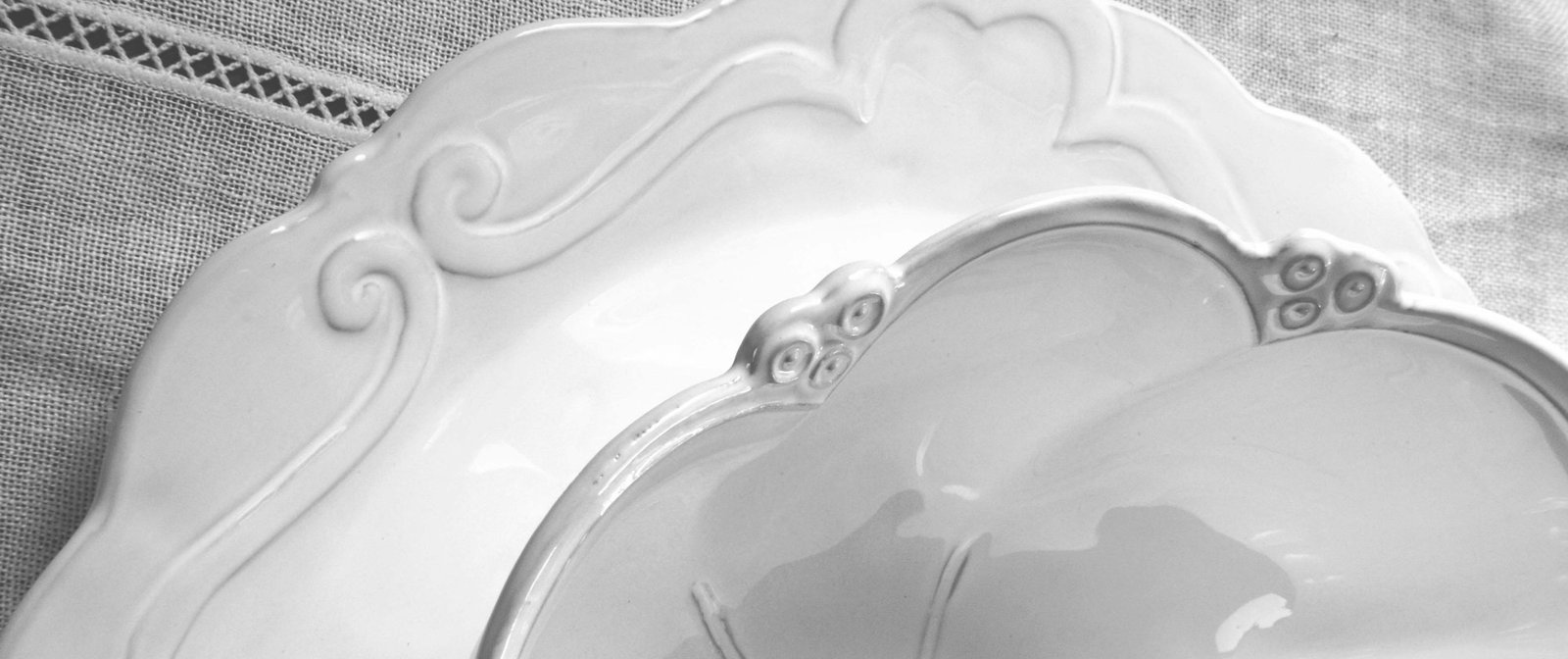 Detail van handgemaakt wit Italiaans servies met subtiel reliëf, gemaakt van hoogwaardig keramiek.